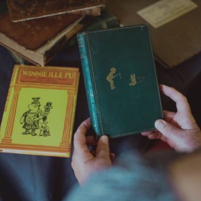 First edition Winne-the-Pooh being held with another book in background. Credit, UQ